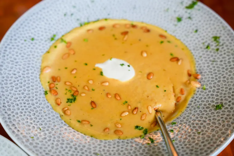 A bowl of creamy orange soup with a spoon